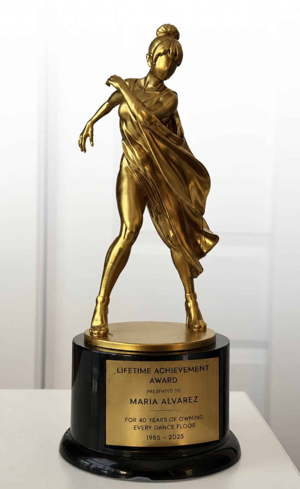 The finished gold trophy on its black base, engraved plate reading Lifetime Achievement Award, presented to Maria Alvarez